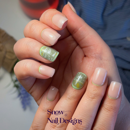 Nude press-on nagels gedragen aan de hand met limoengroene reverse French en een accent nagel met citrus details en een drankje – Fresh Lime van Snow Nail Designs