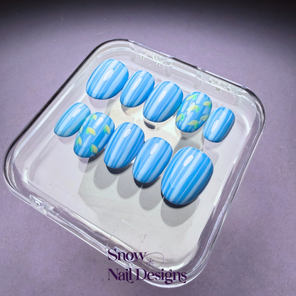 Flatlay foto van blauwe press-on nagels  met lichtblauwe strepen en citroentjes – Limone van Snow Nail Designs