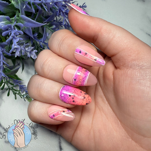 Press-ons met een romige roze-paars ombre en speelse stipjes, gedragen op een hand.