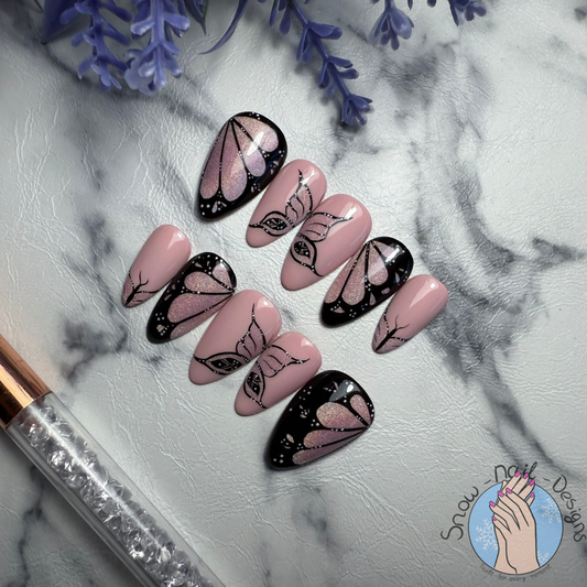 Set van 10 handgemaakte press-on nagels in nude met holografische roze cat eye en zwarte vlindervleugelaccenten.
