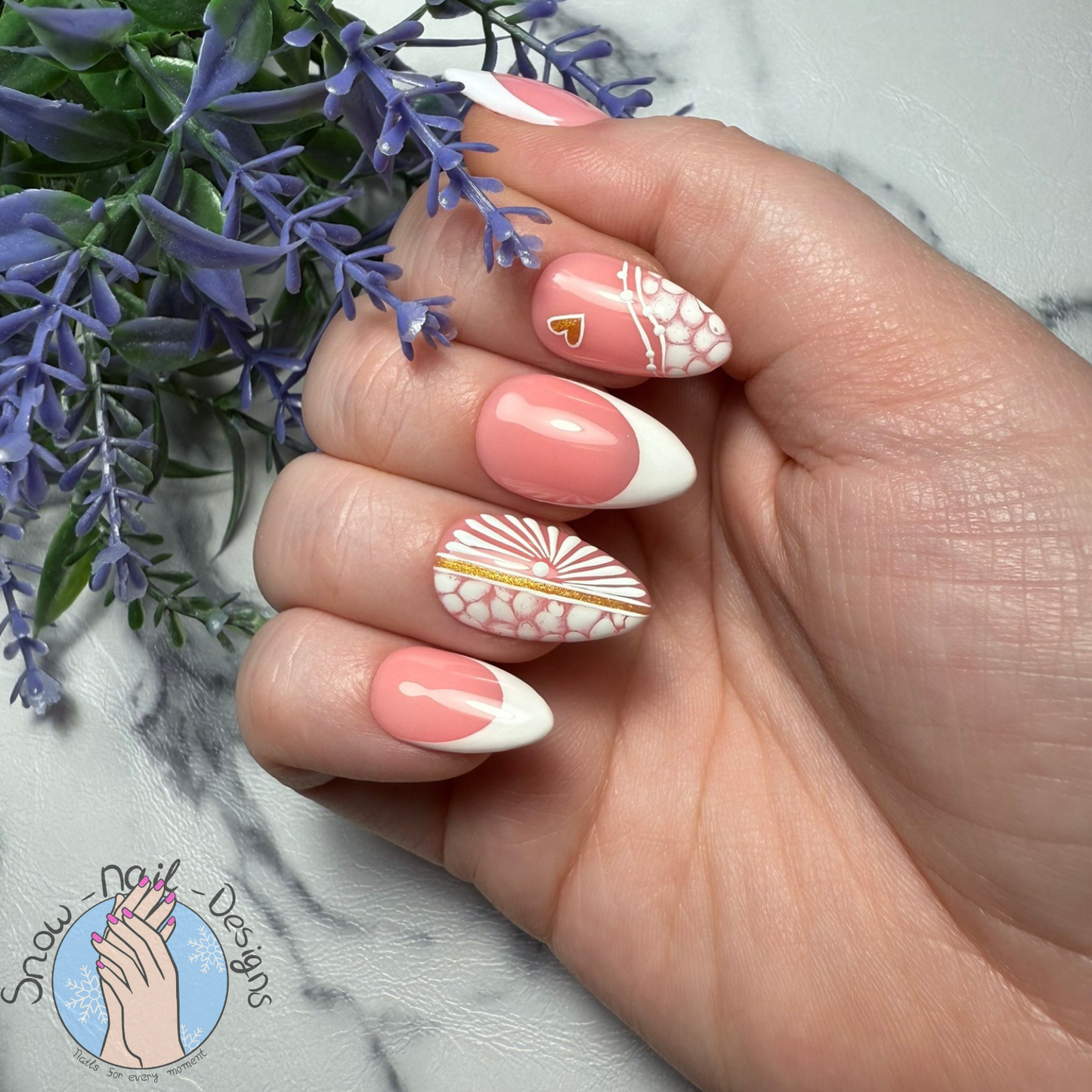 Hand met Sunset Glow press-on nagels in koraalroze en wit, versierd met gouden details en patronen.