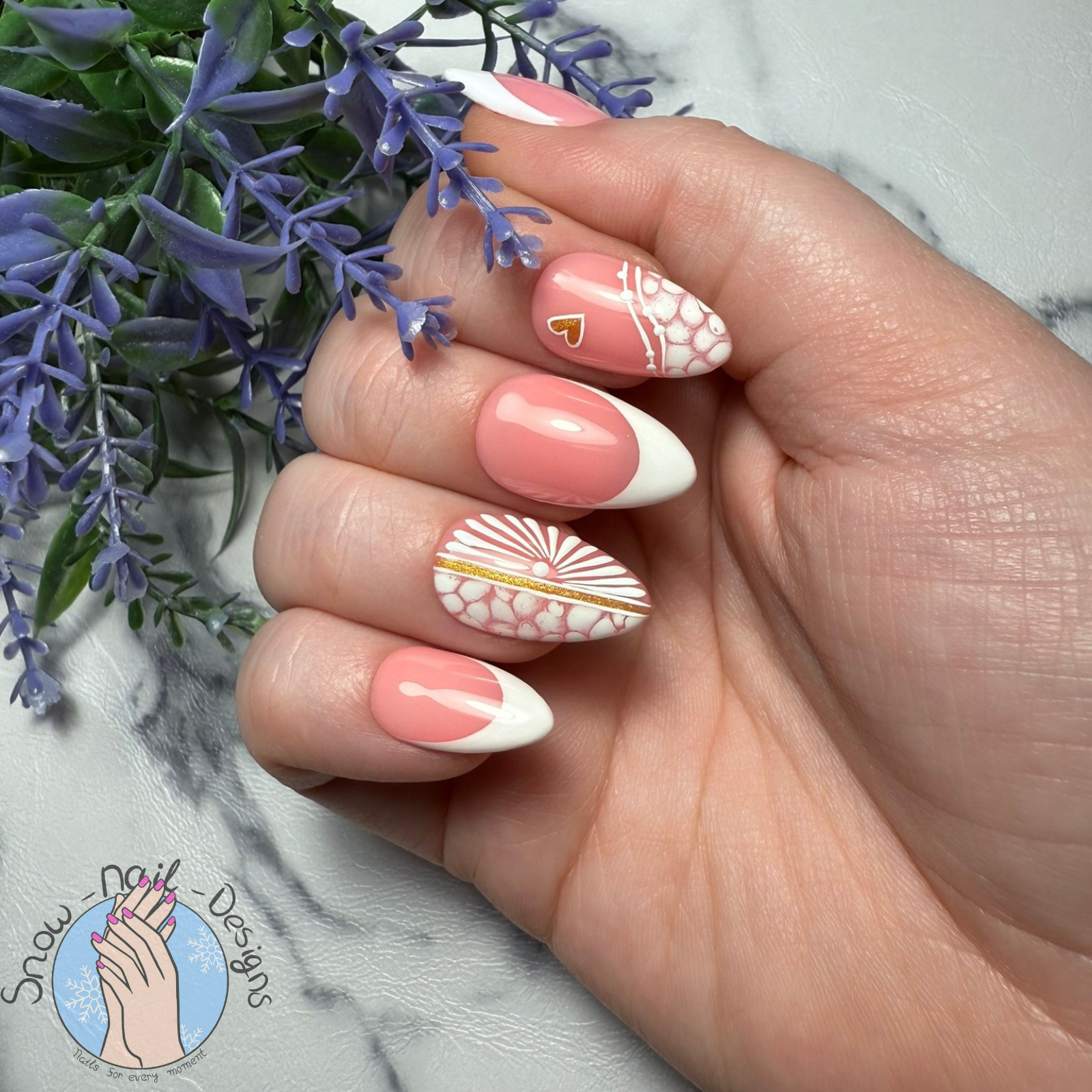 Hand met Sunset Glow press-on nagels in koraalroze en wit, versierd met gouden details en patronen.