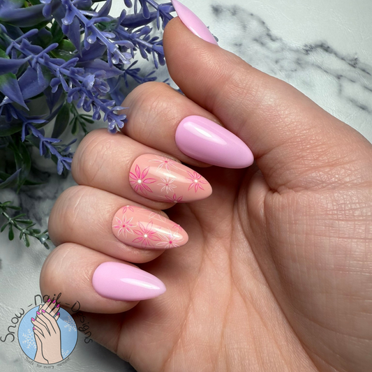 Pastelkleurige press-ons met roze bloemenmotief, gedragen op een hand.