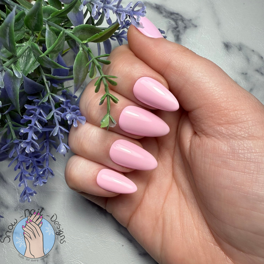 Effen pastelroze press-ons in een frisse en verzorgde look, gedragen op een hand.