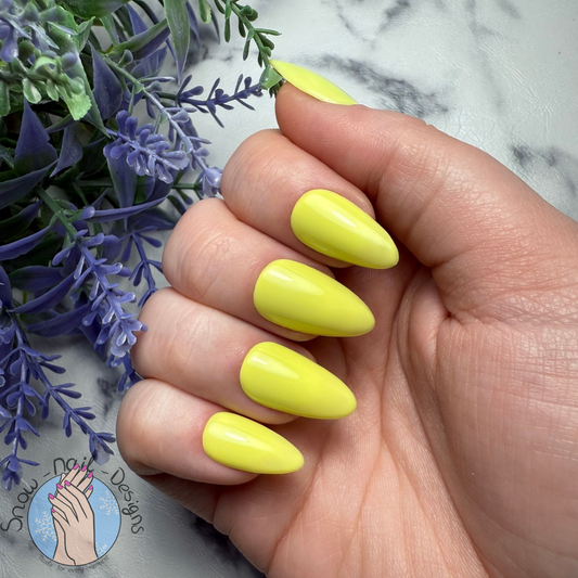 Hand met felgele press-on nagels voor een vrolijke, opvallende look.