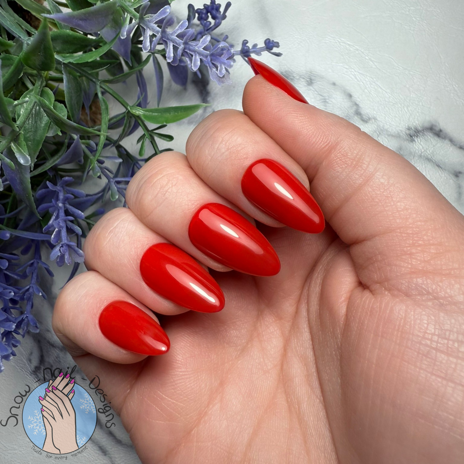 Hand met felrode press-on nagels in een klassieke, krachtige stijl.