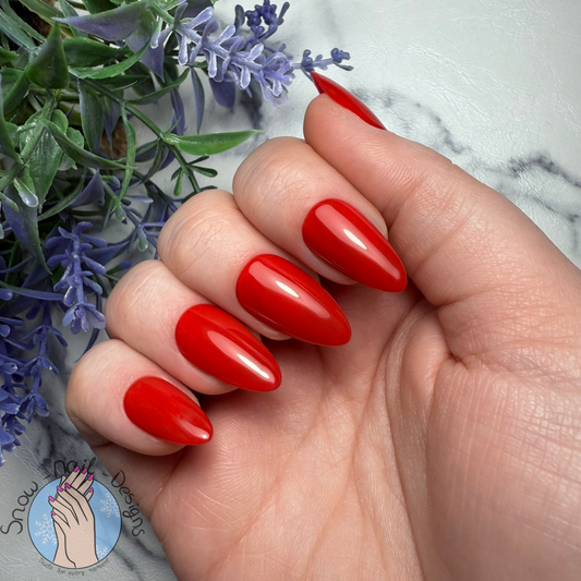 Hand met felrode press-on nagels in een klassieke, krachtige stijl.