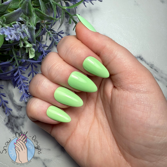 Hand met lichtgroene press-on nagels in een frisse, levendige kleur.