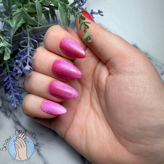 Hand met felroze press-on nagels met een sprankelend cat eye effect.