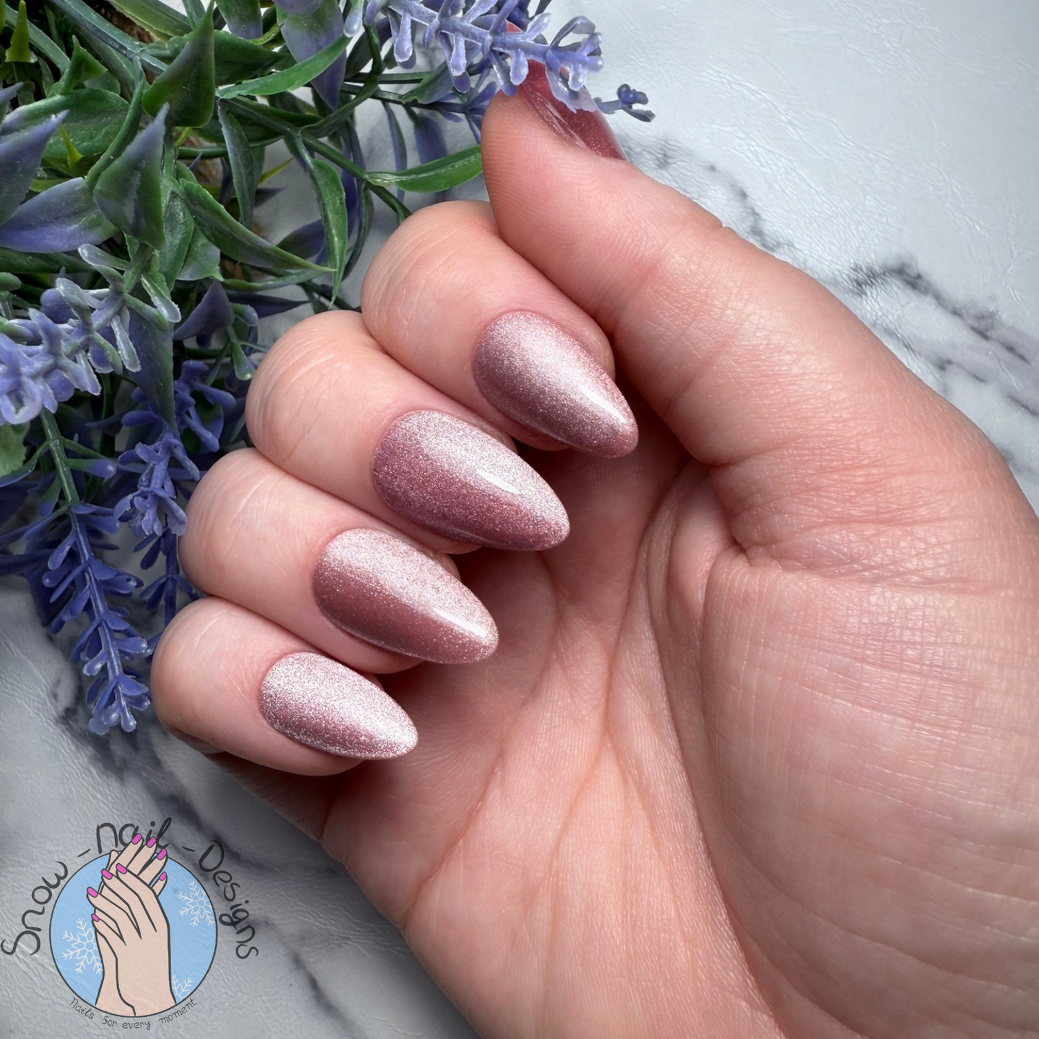 Hand met rosé kleurige press-on nagels met een subtiele shimmer en cat-eye effect